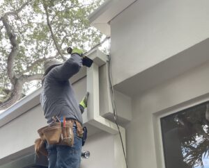 man installing gray rain gutters